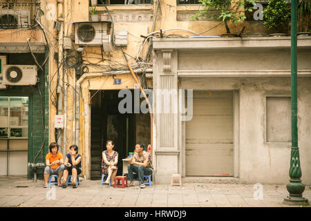 Hanoi, Vietnam - 25. April 2014: Einheimischen ruhen auf Plastikstühlen in der Nähe von ihrem Haus auf der Straße der Altstadt von Hanoi, Vietnam. Stockfoto