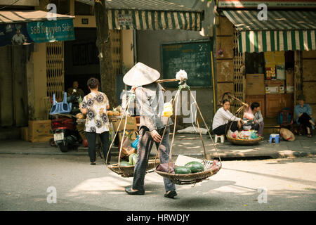 Hanoi, Vietnam - 26. April 2014: Frau Verkäufer tragen Körbe mit Früchten auf der Straße von Hanoi am 26. April 2014, Vietnam. Stockfoto