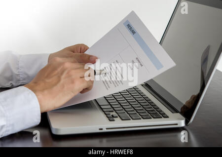 Geschäftsmann oder Arbeitsuchende überprüfen Sie seinen Lebenslauf auf seinem Schreibtisch mit Stift und Computer Laptop. Stockfoto