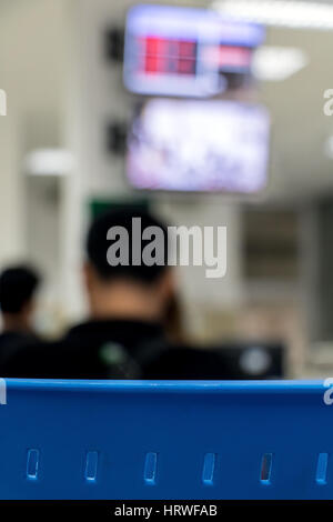 Ein Stuhl mit einem unscharfen Hintergrund-Büro. Die Menschen sitzen unterhalb des Displays mit Zähler der Warteschlange. Stockfoto