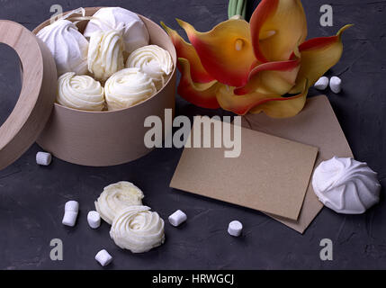 Bouquet von grünen gelben Callas mit Marshmallows in einer Runde Holzkiste auf einem grauen Hintergrund aus Holz Stockfoto