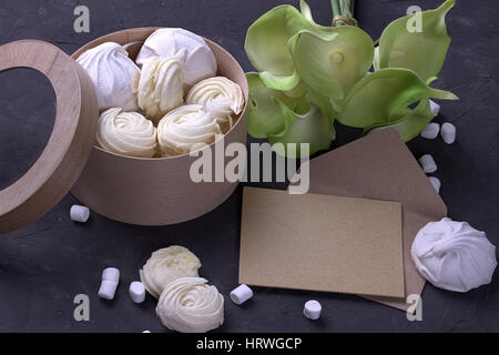 Bouquet von grünen gelben Callas mit Marshmallows in einer Runde Holzkiste auf einem grauen Hintergrund aus Holz Stockfoto