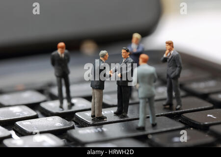 Selektiven Fokus Miniatur Geschäftsmann Handshake Investitionen auf die Schaltfläche Enter Taste Tastatur Hintergrund als Verpflichtung Konzept. Stockfoto