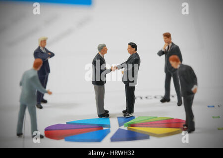 Draufsicht selektiven Fokus Miniatur Business Mann Handshake auf bunten Kreis Diagrammhintergrund als Engagement und Investitionen Konzept. Stockfoto