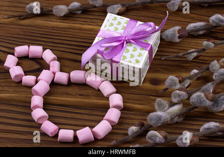 Die 8er-ausgekleidet mit rosa Marshmallow grüne Geschenk Box-Spring Zweige mit Knospen auf einem hölzernen braunen Hintergrund Stockfoto