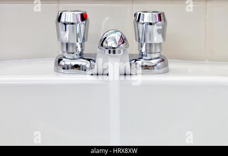 Wasser fließt aus einem wassersparenden Erhaltung Wasserhahn installiert in einer öffentlichen Toilette. Stockfoto