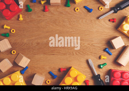 Kinder Spielzeug Rahmenhintergrund. Buntes Spielzeug Werkzeuge, Bau-Blöcke und Würfel auf Holztisch. Ansicht von oben. Flach zu legen. Getönten Bild Stockfoto