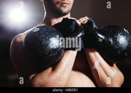 Athlet mit Kettlebells trainieren. schöner muskulöser Mann-Fitness-Workout im Fitness-Studio Stockfoto