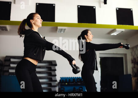 Frauen Kettlebell Training im Fitness-Studio. Zwei Mädchen, die Kettlebell-Übungen. Stockfoto