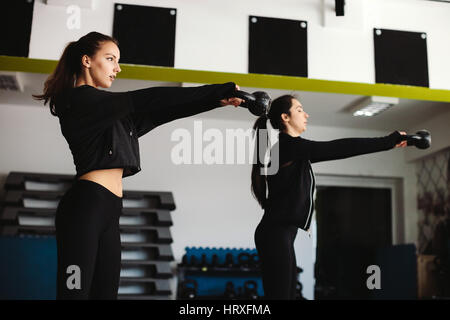 Frauen Kettlebell Training im Fitness-Studio. Zwei Mädchen, die Kettlebell-Übungen. Stockfoto