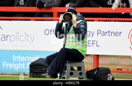 Sportfotograf bei der Arbeit mit einer Canon Kamera und einem langen Teleobjektiv bei einem Fußballspiel bei nassem Wetter nur zur redaktionellen Verwendung. Keine Verkaufsförderung. Für Football-Bilder gelten Einschränkungen für FA und Premier League. Keine Nutzung des Internets/Handys ohne FAPL-Lizenz - für Details wenden Sie sich an Football Dataco Stockfoto