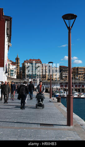 Menschen im Hafen und Blick auf die Skyline der Altstadt an der Strandpromenade von Donostia San Sebastian, der Küstenstadt am Golf von Biskaya Stockfoto