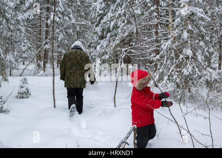 Mutter und Tochter, die zu Fuß in den Winterwald Stockfoto