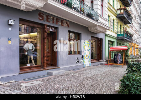 Berlin, Prenzlauer Berg. Straßenszene, Cyroline Upmarket Kleidung Shop, alte erhaltene Ladenschild und El Bocho Street art Stockfoto