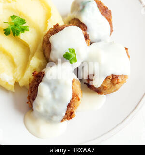 Fleischbällchen mit weißen cremigen Sauce und Maische auf Platte hautnah Stockfoto