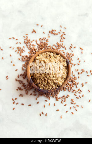 Leinsamen (Boden Leinsamen) zermalmt auf Holzlöffel und weiß Steintisch - gesunde Bio Vegan vegetarisch Lebensmittelzutat Stockfoto