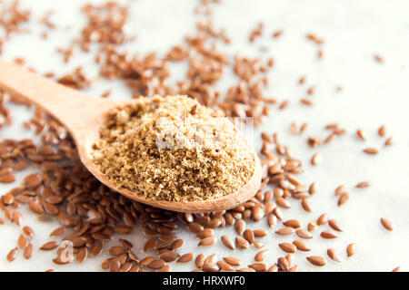 Leinsamen (Boden Leinsamen) zermalmt auf Holzlöffel und weiß Steintisch - gesunde Bio Vegan vegetarisch Lebensmittelzutat Stockfoto