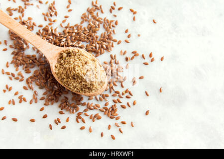 Leinsamen (Boden Leinsamen) zermalmt auf Holzlöffel und weiß Steintisch - gesunde Bio Vegan vegetarisch Lebensmittelzutat Stockfoto