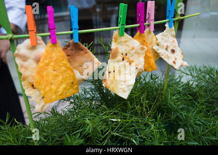Kreative foodstyling von Nachos und Fladenbrot hing mit farbigen Clips Stockfoto