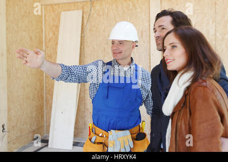 Vorarbeiter zeigt neues Haus, ein junges Paar Stockfoto