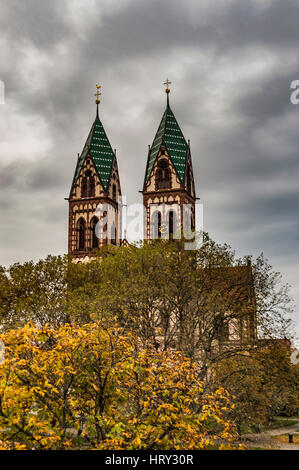 Herz-Jesu-Kirche Twin überragt von Freiburg Bahnhof an trüben Novembermorgen Kirche. Stockfoto