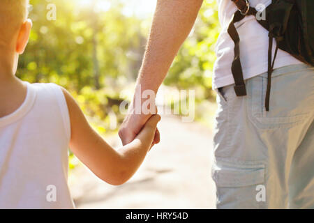 Kind an Hand der Erwachsenen Elternteil außerhalb im Sommerpark Stockfoto