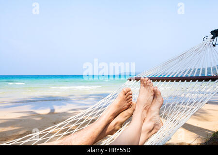 Urlaub mit der Familie am Strand, die Füße des Paares in der Hängematte, Entspannung Hintergrund Stockfoto