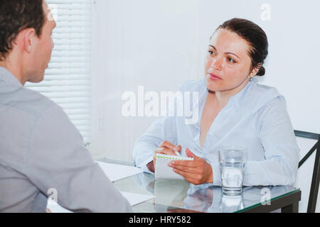 Vorstellungsgespräch in modernen Firmensitz, strenge Frau junger Mann anhören Stockfoto