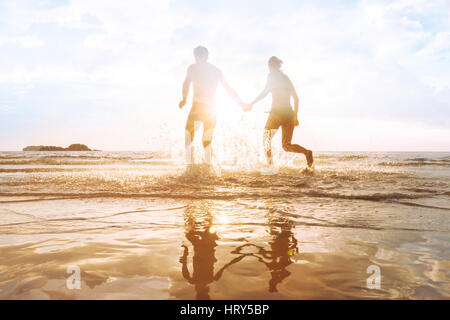 glückliche junge Paare, die Spaß am Strand bei Sonnenuntergang, Spritzwasser, das Leben genießen