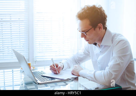 Geschäftsmann lesen und Vertragsunterzeichnung in modernen, hellen Büro Stockfoto