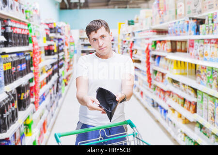 Mann zeigt leere Brieftasche im Supermarkt, kein Geld zu kaufen, teure Lebensmittel einkaufen Stockfoto