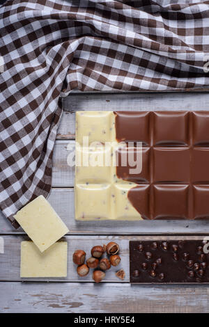 Stücke der Fliese Schokolade, Nüssen und Kakaobohnen auf hölzernen Hintergrund Stockfoto