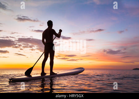 Paddleboard am Strand bei Sonnenuntergang, Paddel stehen in Thailand Stockfoto
