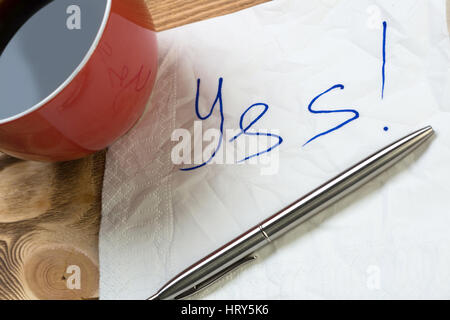 Kaffee Tasse Kugelschreiber und Serviette mit Worten auf hölzernen Tisch Stockfoto