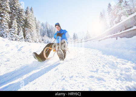 Schlitten, Winter Schnee Urlaubsaktivität, junger Mann Spaß Rodeln Stockfoto