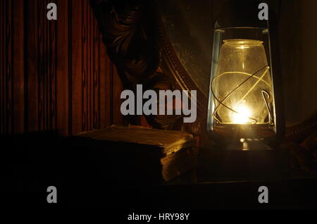 Buch, Öl-Lampe und Spiegel im Dunkeln Stockfoto