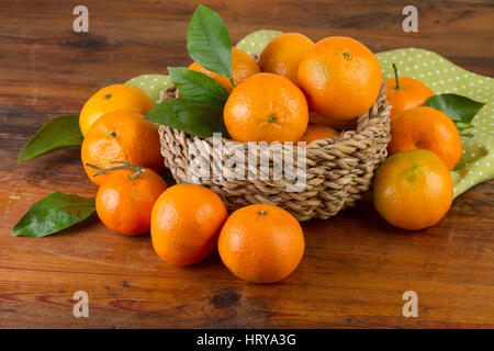 Korb mit Mandarinen mit grünen Serviette auf alten hölzernen Hintergrund Stockfoto