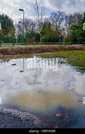 Eine schlammige Pfütze im Prospect Park in Reading in dem Himmel und Umgebung als Spiegelbild gesehen werden können. Stockfoto