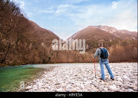 Wanderer am Ufer eines Flusses. Wandern in Richtung Berg. Rambler etwa 60 Jahre alt. Stockfoto