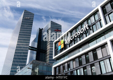 München, Deutschland. 6. März 2017. Das Microsoft-Logo an der Fassade des neuen Miscrosoft-Deutschland-Zentrums in München, 6. März 2017. Im Hintergrund ist die Highlight Towers mit Fujitsu und IBM-Logos. Foto: Matthias Balk/Dpa/Alamy Live News Stockfoto