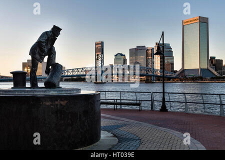 Die Lone Sailor Statue und Stadt Skyline von Southbank Riverwalk entlang der St. Johns River bei Sonnenuntergang in Jacksonville, Florida. Stockfoto