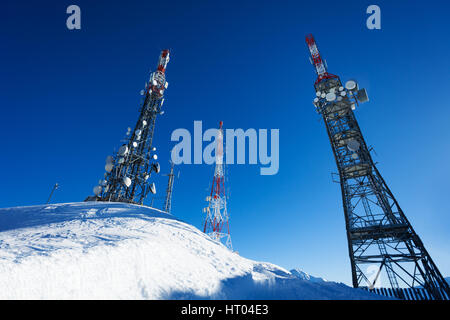 Baum-Telekommunikation-Türme auf schneebedeckten Berg gegen blauen Himmel Stockfoto