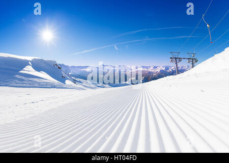 Frische Spuren von Snowcat im Skigebiet Pisten am frühen sonnigen Morgen Stockfoto