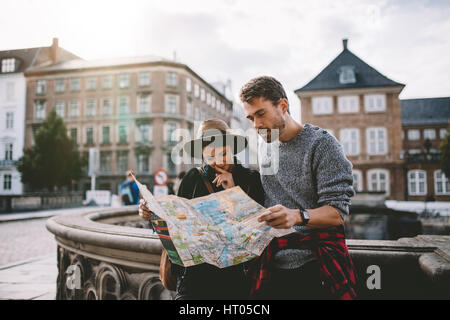 Junges Paar eine Navigationskarte der Stadt betrachten. Touristen finden ihren Weg auf einer Karte, die auf der Straße steht. Stockfoto