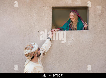 traditionell gekleideten omanischen Cuple Hand in Hand durch ein Fenster auf ein altes Haus Stockfoto