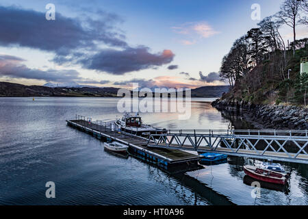 Cuillin Hills Mountain Range, über Loch Portree, auf der Isle Of Skye, Schottland, gegen einen dramatischen Himmel vor Portree Hafen Anlegestelle. Stockfoto