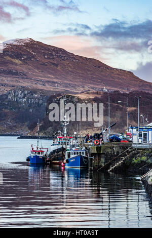 Ben Tianavaig über Loch Portree, auf der Isle Of Skye, Schottland, gegen einen dramatischen Himmel, Blick vom Hafen am Pier und Angelboote/Fischerboote Stockfoto