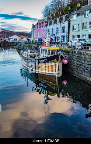 Fischerboot im Hafen von Portree, vor farbigen Häusern, mit Reflexion im Meer Stockfoto