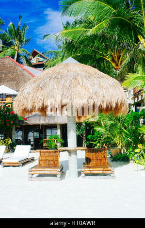 Nipa-Hütte-Sonnenschutz mit zwei Bambus Liegestühle am weißen Korallen sand Strand Stockfoto