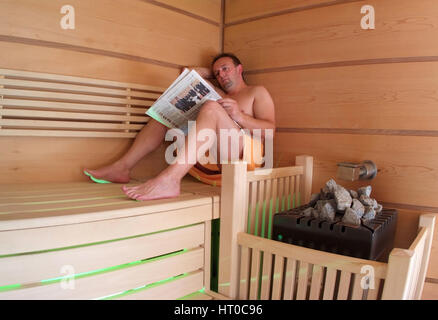 Mann liest Zeitung im Sauna - Frau in Sauna Stockfoto